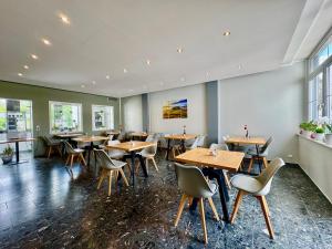 a restaurant with wooden tables and chairs and windows at Villa Heusenstamm in Heusenstamm