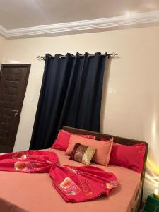 une chambre avec un lit aux draps rouges et un rideau noir dans l'établissement Ciel bleu, à Dakar