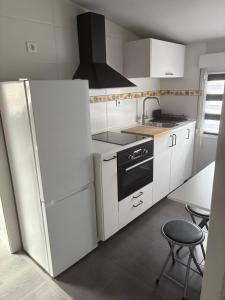 桑坦德Ático recién reformado en Santander的白色的厨房配有冰箱和桌子