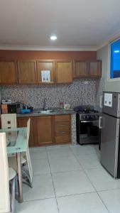 a kitchen with wooden cabinets and a black refrigerator at Mitaly Apartamentos 111 in Santo Domingo +40 photos
