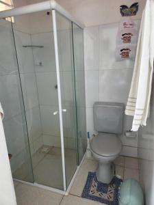 a bathroom with a toilet and a glass shower at Flat Lagoa Azul in Maragogi