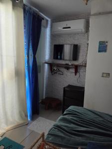 1 dormitorio con 1 cama y TV en una pared de ladrillo en Flat Lagoa Azul, en Maragogi
