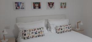 a white bed with two pillows and pictures on the wall at CIVICO 16A - Apartment - with private parking in Quartu SantʼElena