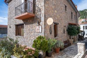 a stone building with a balcony and plants at Ξενώνας Οντάς & Spa in Arachova
