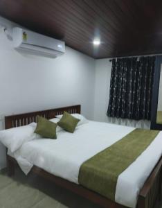 een slaapkamer met een groot wit bed met groene kussens bij 2 Bedroom villa in Mūvattupula