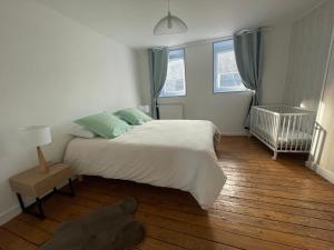 a bedroom with a large bed and a crib at Comfort with garden in Fécamp