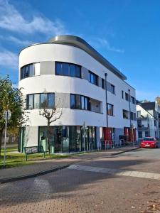 a white building with a red car parked in front of it at Ferienwohnung Meer-Zeit in Lubmin