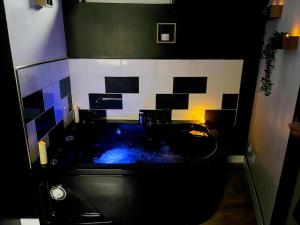 a bathroom with a black tub with blue water at CY L'unique instant in Wingles