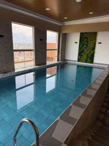 a swimming pool with blue tile floors and windows at El departamento de Verito in Cochabamba