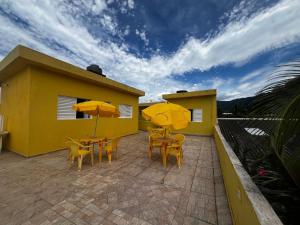 een terras met gele tafels, stoelen en parasols bij Recanto Guaraú 4 in Peruíbe