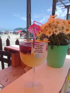 een drankje in een glas zittend op een tafel met bloemen bij Recanto Guaraú 4 in Peruíbe