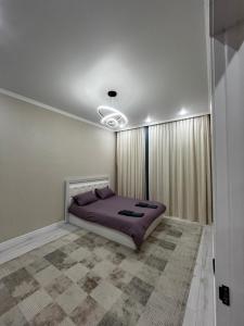 Квартира في Taldykolʼ: غرفة نوم مع سرير مع أغطية أرجوانية وستائر