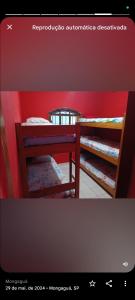 two bunk beds in a room with a red wall at Casa top com piscina em Mongaguá in Mongaguá