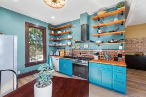 a kitchen with blue cabinets and wooden shelves at Historic French Royal Estate at Capitol, Downtown! in Austin
