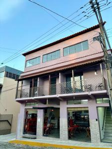 Pousada Recanto das Bromélias في ساو ثومي داس ليتراس: مبنى وردي مع شرفة وطاولة