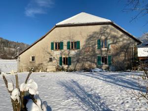 a building with green shuttered windows in the snow at La ferme d'Auguste in Thorens-Glières