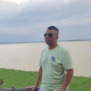 Un hombre con gafas de sol de pie frente a un cuerpo de agua. en Suite property insurance groups of company, en Dhaka