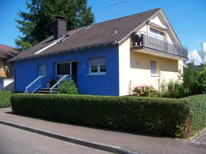 ein blau-weißes Haus mit einem Balkon in der Unterkunft Ferienwohnung Villringer in Orschweier