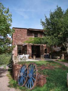 an old stone house with a large wheel in front of it at Domaine la Pause in Aveyron in Vabres-lʼAbbaye