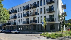 un grand bâtiment blanc avec des voitures garées dans un parking dans l'établissement Black Lotus 4 I City Centre I Free Parking l 24hr Access, à Banská Bystrica