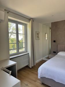 a bedroom with a bed and a large window at Villa du Parc de Scey in Dole