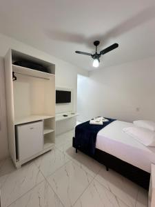 Pousada Recanto das Bromélias في ساو ثومي داس ليتراس: غرفة نوم مع سرير وتلفزيون بشاشة مسطحة