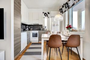 a white kitchen with a dining table and chairs at Adorable Arctic Apartments - Private Sauna & Free Parking in Rovaniemi