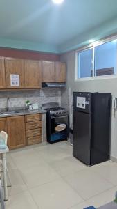 une cuisine avec un réfrigérateur noir et une cuisinière dans l'établissement Mitaly apartamentos RD H, à Saint-Domingue