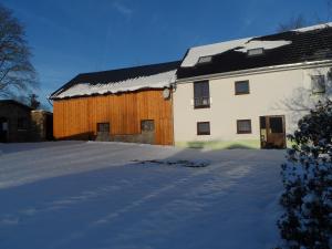 una casa con tetto coperto di neve in un cortile di De Ploeg a Manderfeld