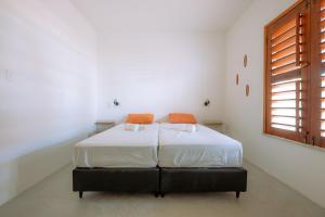 ein Schlafzimmer mit einem Bett mit weißen Laken und orangefarbenen Kissen in der Unterkunft Casa Iguana in Trairi + 21 Fotos