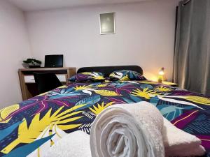 ein Schlafzimmer mit einem bunten Bett, auf dem ein Handtuch liegt in der Unterkunft Maison Moderna-8 personnes-WiFi-Centre ville in Fontenay-le-Comte