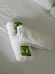 Pousada Recanto das Bromélias في ساو ثومي داس ليتراس: زوج من المناشف البيضاء مع مربعات خضراء على السرير