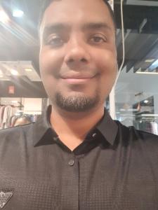 Un hombre con barba sonríe a la cámara. en Suite Property Insurance Group Of Company, en Dhaka