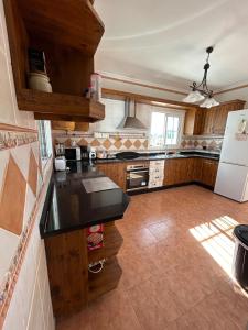 eine Küche mit Holzschränken und einer schwarzen Arbeitsplatte in der Unterkunft CASA RURAL MALAGA,VILLA FAMARA,10 personas,DESAYUNO ANDALUZ INCLUIDO EN EL PRECIO in Málaga