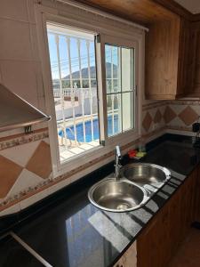 eine Küchentheke mit Spüle und Fenster in der Unterkunft CASA RURAL MALAGA,VILLA FAMARA,10 personas,DESAYUNO ANDALUZ INCLUIDO EN EL PRECIO in Málaga