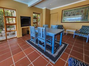 una sala da pranzo con tavolo e sedie blu di Villa Candle Berry - Tranquil Lagoon Retreat a Brenton-on-Sea