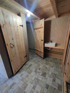 a bathroom with a sink and wooden doors at Sustainable Samel's Cottage Hrid's lake Prokletije in Plav