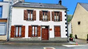 Maison blanche avec portes et fenêtres marron dans l'établissement Résidence Les Pâquerettes N3, à Le Mont-Dore