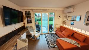 een woonkamer met een oranje bank en een glazen schuifdeur bij Anton's Home in LʼHay-les-Roses