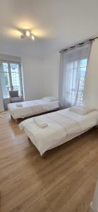 three beds in a room with white walls and wood floors at Le Charme du Sanctuaire 8 couchages 400m de la Grotte in Lourdes