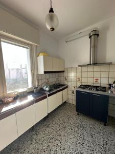 une cuisine avec des placards blancs, une fenêtre et une cuisinière dans l'établissement Tre Aceri Comfort House, à Udine