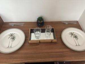 deux assiettes et deux verres sur une table en bois dans l'établissement Transamérica Executive Campos dos Goytacazes, à Campos dos Goytacazes