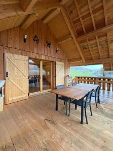 une grande table en bois sur une terrasse en bois avec des chaises dans l'établissement La Cabane de Sophie - Nature et Calme, à Saint-Cernin