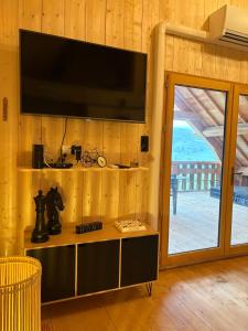 un salon avec une télévision sur un mur en bois dans l'établissement La Cabane de Sophie - Nature et Calme, à Saint-Cernin