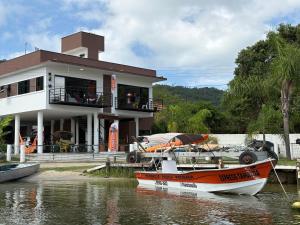 a boat in the water in front of a house at Pousada Tamatoa in Florianópolis