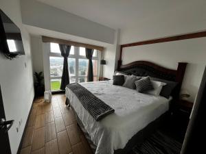 una camera da letto con un letto grande e una grande finestra di Luxury living Sarabela Altos de Occidente, Interplaza Xela a Quetzaltenango