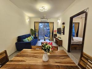 Serene 1BHK Getaway Apartment in Candolim Goa with Pool, Balcony & Kitchen في كاندوليم: غرفة معيشة مع أريكة زرقاء وطاولة