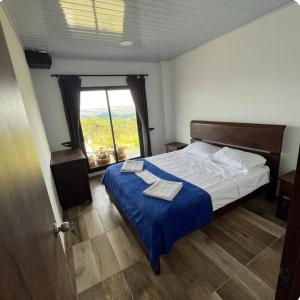 a bedroom with a bed with a blue blanket and a window at Casa guardían del bosque in San Gil