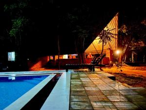 a swimming pool at night with a bench next to it at Ali Adi Eco Resort in Sigiriya