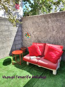 a red couch sitting on the grass next to a wall at Rinconcito Rural con encanto en Las Hayas by Vapagó Tenerife in Acardece